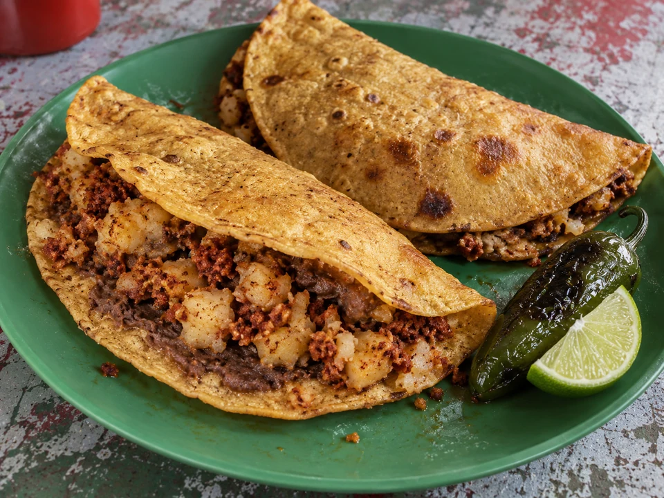 Two fried folded corn tortillas filled with beans, potato and chorizo.